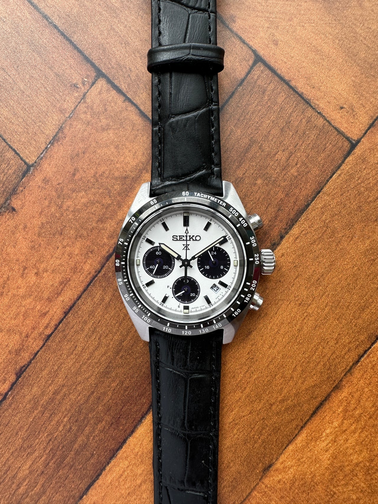 Wristwatch with black strap and silver case on a wooden surface