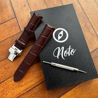 Thumbnail for Brown watch strap with silver clasp on a black leather notebook with 'Noto' branding.