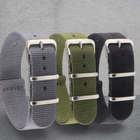 Thumbnail for Three NATO watch straps in grey, green, and black with silver buckles on a grey background